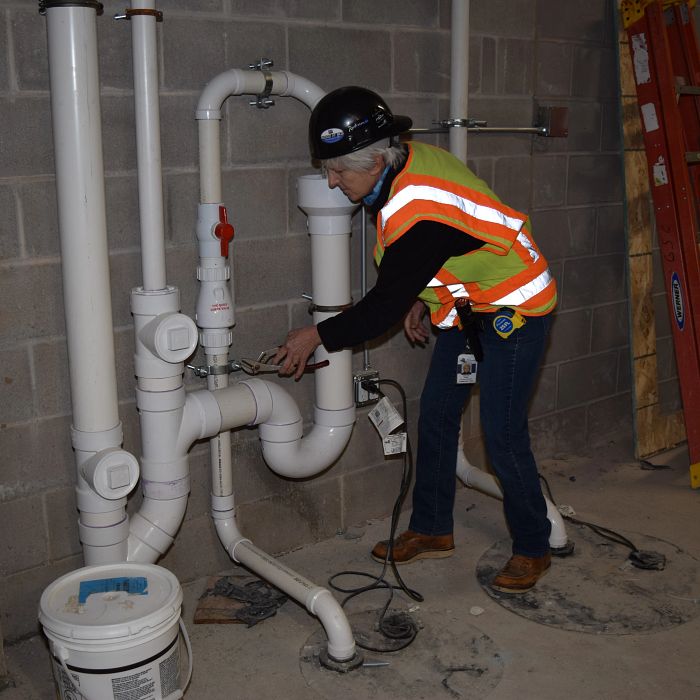 Rebecca Ames working on plumbing
